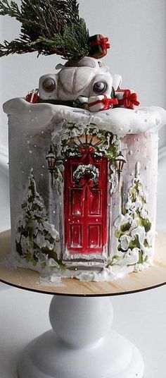 a decorated cake with a red door and snowflakes on the top is sitting on a pedestal