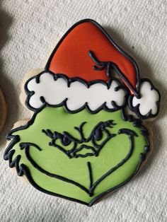 the grin face cookie is decorated with black icing and red santa's hat