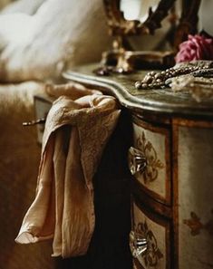 an old dresser with jewelry on it and a mirror in the back ground next to it