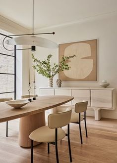 a dining room table with four chairs and a bowl on it in front of a large window