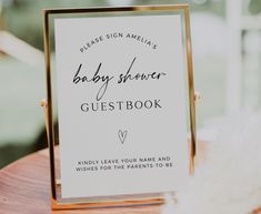 a baby shower guest book sitting on top of a wooden table