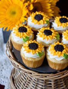 cupcakes with sunflowers on them sitting in a wicker basket