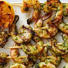 grilled shrimp and broccoli skewers with lemon wedges on a white platter