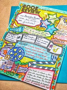 a book review is shown on top of a blue folder with colorful writing and pictures