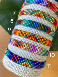 a stack of bracelets sitting on top of a table next to a green leaf