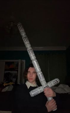 a person holding up a large cross made out of newspaper strips in front of their face