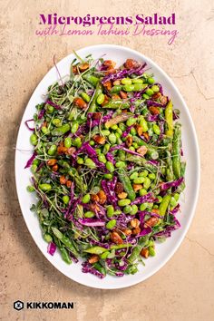 a white plate topped with green beans and purple slaw next to a fork on top of a table