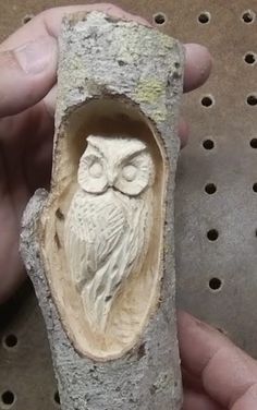 an owl carved into a rock with holes in the ground and one hand holding it