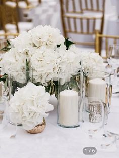 white flowers in vases and candles on a table