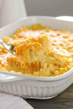 a spoon full of macaroni and cheese being lifted from a casserole dish