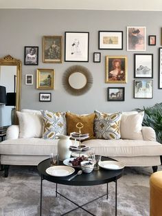 a living room filled with lots of pictures on the wall and furniture in front of it