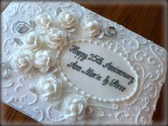 a wedding cake with white flowers on it and the words happy 25th anniversary written in black