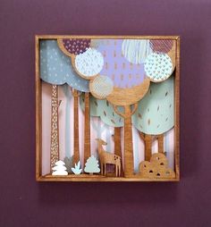 a wooden box with cut out trees and animals in the woods on purple wallpaper