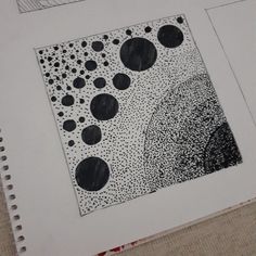 an art work with black and white circles on paper next to a pencil drawing book