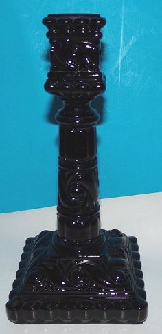 a black candle holder sitting on top of a white table next to a blue wall