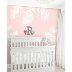 a baby's room decorated in pink and white with palm leaves on the wall