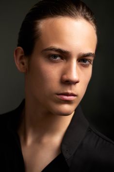 a young man in black shirt looking at the camera with serious look on his face