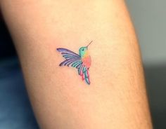 a colorful hummingbird tattoo on the arm