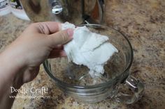 someone is removing cotton from a glass cup