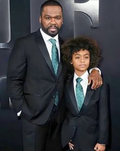 a man in a suit and tie standing next to a young boy