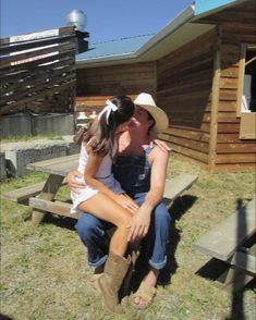 a woman sitting on top of a wooden bench next to a man wearing a cowboy hat