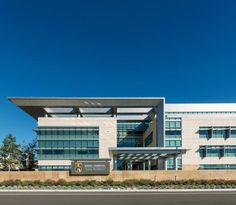 an office building on the side of a road with blue sky in the back ground