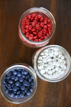 three jars filled with red, white and blue candies on top of a wooden table