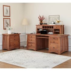 a wooden desk sitting on top of a hard wood floor next to a white rug