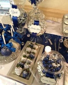 blue and white desserts are on display at a table with silverware, candles and candy