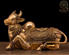 a golden cow figurine sitting on top of a wooden table next to a black background