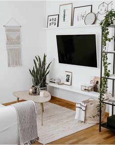 a living room with white walls and wooden floors, a large flat screen tv mounted on the wall