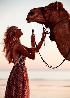 a woman in a dress is holding a camel