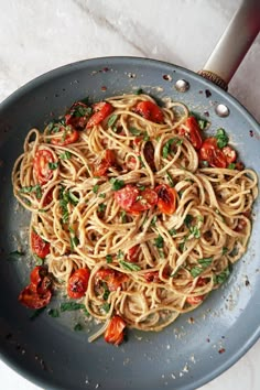 a plate of pasta with tomatoes and herbs