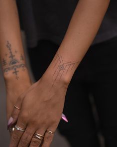 two hands holding each other with tattoos on them