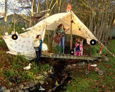 people are playing music on a bridge in the woods near a pond and a tent