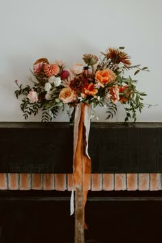 a bouquet of flowers is tied to a fireplace mantel by a ribbon on the mantle