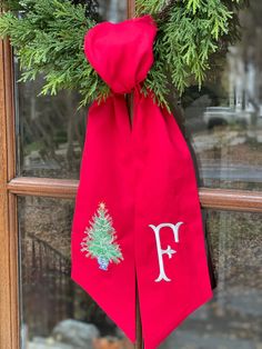 a christmas wreath hanging on a door with the letter f in it and a pine tree