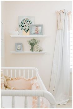 a baby's room with pink and white decor on the wall, crib in foreground