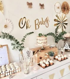 a dessert table with cupcakes, cakes and other items on it at a baby's first birthday party