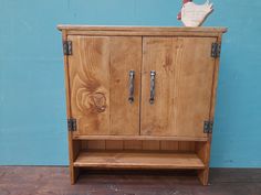 a wooden cabinet with two doors and handles on the front, against a blue wall