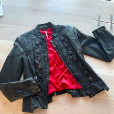 a black leather jacket and red shirt sitting on top of a wooden floor