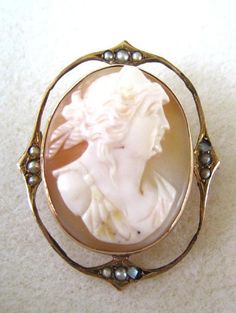 "Fantastic brooch featuring a cameo portrait bust set in a 10K yellow gold frame. What makes this pin/pendant so beautiful is the wire frame surrounding it set with cultured seed pearls at the 12, 3, 6, and 9 o'clock positions. There is a bail on the back of the pin that folds down so you can wear this piece as a pin or a pendant. Marked 10K with a makers mark, an 's' in an oval. In excellent condition with light wear. No cracks or chips in the cameo. Measures 1 1/2\" by 1 1/4\"." Art Nouveau Oval Cameo Jewelry, Gold Cameo Jewelry In Art Nouveau Style, Art Nouveau Cameo Jewelry Gift, European Cut Diamond Ring, Buyable Pins, Coral Beads Necklace, Rhinestone Tiara, Fun Photos, Cameo Jewelry