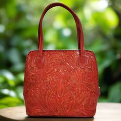 This stunning hand-tooled leather bag in a vibrant red color is a true statement piece. Handmade  with love and care by talented artisans. Each detail of the bag has been meticulously handcrafted by skilled artisans, creating a unique and one-of-a-kind design.   Add a pop of color to your outfit with this exquisite hand-tooled leather handbag. height:29 cm.  11 1/2 inches width at the bottom: 30cm.  12-inches base:12.5 cm.  5 inches straps: 21cm    8 inches interior: suede leather zippered at th Traditional Red Top Handle Bag, Artisan Red Tote Shoulder Bag, Artisan Red Shoulder Bag For Everyday Use, Artisan Red Leather Bags, Artisan Red Bags For Everyday Use, Red Bag With Leather Lining As Gift, Red Hand Tooled Shoulder Bag For Daily Use, Red Hand Tooled Bag For Daily Use, Red Shoulder Bag With Leather Lining As Gift