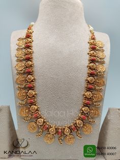 a gold necklace with red beads and coins on display at a jewelry store in india