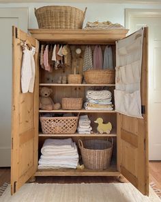 an open closet with baskets, clothes and blankets on the shelves in front of it