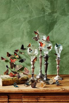 an assortment of glass and metal objects on a table with green wall in the background