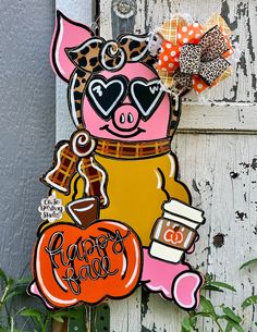 a door hanger with an image of a pig holding a pumpkin and wearing sunglasses