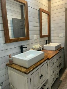 a white sink sitting on top of a wooden counter next to a mirror and two sinks