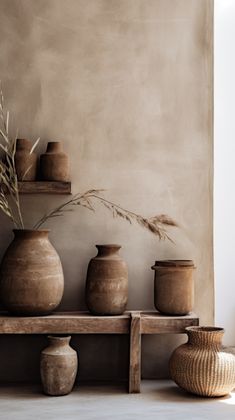 some vases are sitting on a shelf in front of a wall