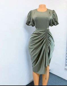 a mannequin wearing a green dress with a knot at the waist and short sleeves